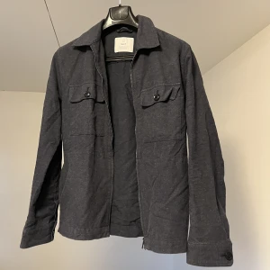 Vår-/sommarjacka från Bläck  - Säljer en stilig vår- och sommarjacka från märket Bläck. Jackan har en riktigt läcker passform och är i storlek S.  Använd fåtal gånger och i mycket gott skick!