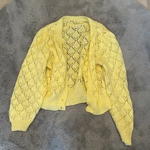 Gul stickad kofta med hålmönster - Superfin gul stickad kofta med öppet hålmönster och ribbade muddar. Koftan har långärmad passform 