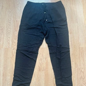 Svart pull-on byxa med snörning - Svarta pull-on byxa med elastisk midja och snörning framtill. Byxorna har en slim passform och är tillverkade i mjukt material. Perfekta för chill dagar eller när du vill vara bekväm men ändå se snygg ut