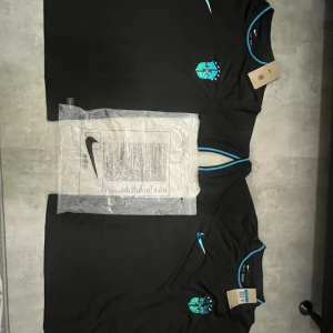 Svart Brasilien fotbollströja  - Helt nya snygga svarta Brasilien fotbollströja från Nike i Dri-FIT-material. Tröjan har korta ärmar, blå detaljer vid krage och ärmslut samt ett blått CBF-märke på bröstet. Perfekt för dig som vill sticka ut på planen eller visa support för Brasilien.