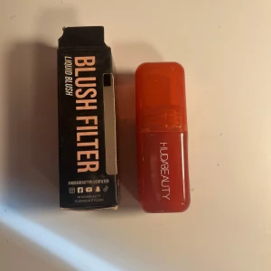 Huda Beauty Blush Filter Liquid Blush - Har endast testat rougen en gång, därav är den helt full. Den är i färgen Watermelon Pop.   Flytande rouge från Huda Beauty i en snygg röd-orange plastförpackning med genomskinligt lock. Blush Filter ger en fräsch och naturlig färg till kinderna och är enkel att applicera tack vare sin smidiga formula. Perfekt för dig som vill ha ett glow och färg på kinderna. 