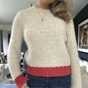 Beige stickad tröja med röd kant - (Reserverad) Säljer en mysig stickad tröja i beige med ribbad röd kant vid midjan och ärmsluten!! Bilden är lånad, men kan absolut skicka fler bilder❤️