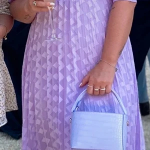 Ljuslila långklänning från ASOS DESIGN - Säljer en drömmig ljuslila långklänning från ASOS DESIGN med geometriskt mönster. Klänningen har puffiga korta ärmar, hög hals och ett tunt yttertyg med en matchande underklänning