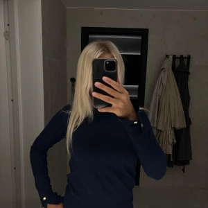 Marinblå stickad tröja Holly & Whyte - Snygg marinblå stickad tröja från Holly & Whyte by Lindex, med dekorativa knappar vid ärmsluten. Perfekt för dig som gillar klassisk stil!!