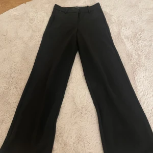 Svarta kostymbyxor från Vero Moda - Snygga svarta kostymbyxor från Vero Moda med klassisk rak passform och breda ben. Byxorna har hällor för bälte och en stilren design som funkar till många olika looks. Materialet känns mjukt och har en lätt stretch för extra komfort. Hör gärna av dig vid frågor osv 💗