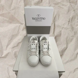 Valentino Opens vita - Vita Valentino Garavani Rockstud sneakers i skinn med silvernitar. Använda max 5 gånger, i mycket fint skick. Nypris ca 8000 kr. Mitt pris: 2499kr!🤩🙌 vid frågor/funderingar, är det bara att skriva!