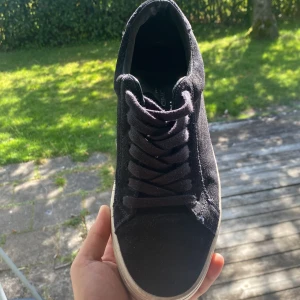 Vagabond mocka skor - Säljer ett par stilrena svarta sneakers från vagabond med ovandel i mjuk mocka och klassisk snörning. Skorna har en vit platt sula som ger en clean look och passar perfekt till jeans eller shorts. Rund tå och låg profil för en chill vibe.