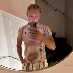 Randig t-shirt från HL Jeans & Co - Säljer en snygg t-shirt från HL Jeans & Co i storlek S. T-shirten är vit med röda horisontella ränder och har gråa muddar vid ärmar och hals. Klassisk passform med korta ärmar och mjukt bomullsmaterial. Perfekt för dig som gillar retrovibbar och stilren design.