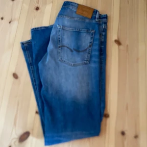 Blå jeans - Snygga blå jeans från Jack and Jones med klassisk femficksdesign och ljusare tvätt på låren. Jeansen har rak passform och är tillverkade i slitstarkt denim. Perfekt för dig som gillar en enkel och tidlös stil. Otroligt bra skick använd endast ett fåtal tillfällen.