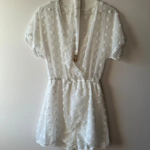 Jumpsuit från Dennis Maglic - Supersöt vit jumpsuit från Dennis Maglic i storlek S, med prickigt mönster och omlott-design.