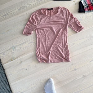 Rosa ribbad topp från Å - Säljer en ljusrosa ribbad topp från Å i storlek XS. Toppen har rund halsringning och trekvartsärm, perfekt för dig som gillar en enkel men snygg look. Materialet är mjukt och stretchigt, vilket gör den skön att bära hela dagen.