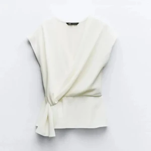 Vit omlopptopp från Zara - Populär vit omloptopp (med knytdetalj) från Zara som säljs då den är för liten för mig. Knappt använd och i gott skick 💕☺️