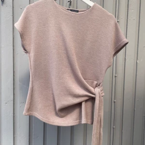Beige stickad topp med knyt från Zara - Supersnygg beige stickad topp från Zara med korta ärmar och rund hals. Perfekt att styla med jeans nu till hösten! Använd 2 gånger💗