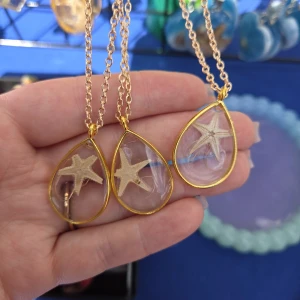 Halsband med stjärnformad berlock - Unika halsband med droppformad berlock i transparent akryl och guldfärgad kant. Inuti berlocken finns en liten beige sjöstjärna som ger en cool strandkänsla. Kedjan är guldfärgad och passar perfekt till sommarens alla outfits. Handgjorda med kärlek, skriv vilken du vill ha vid köp.