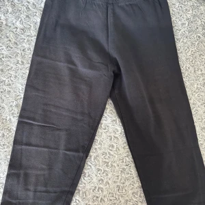 Svarta cykelbyxor från Decathlon - Svarta cykelbyxor  från Decathlon med elastisk midja och trycket 'TODAY I CHOOSE JOY' i rosa längs ena benet. Sköna och enkla att dra på, perfekta för chill eller träning. Materialet är mjukt och stretchigt, vilket gör dem riktigt bekväma.