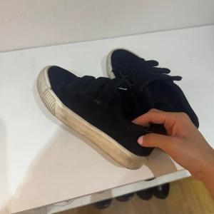 Svarta sneakers i manchester med kardborre - Svarta sneakers i manchestertyg med tre breda kardborreband och vit, räfflad gummisula. 