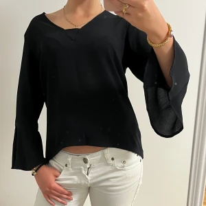 Svart blus med vida ärmar  - Snygg svart blus med v-ringning och vida, svängda ärmar! Köpt utomlands. 