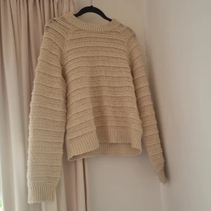 Beige stickad tröja från SAMSA - Mysig beige stickad tröja från SAMSA Collection i storlek S. Tröjan har ett snyggt ribbat mönster, rund halsringning och långa ärmar. Perfekt för lager-på-lager och chill höst- eller vinterstil.
