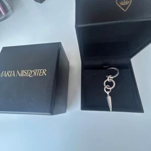 Silverörhänge Maria Nilsdotter spike - Coolt örhänge från Maria Nilsdotter i silver med två ringar och en spetsig spike-hängare. Snygg minimalistisk design som sticker ut och passar perfekt för dig som gillar edgy smycken. Levereras i original ask.
