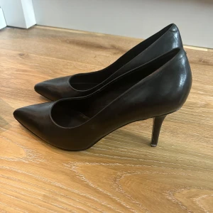 Svarta pumps från Tiger of Sweden - Klassiska svarta pumps i skinn från Tiger of Sweden. Snygg spetsig tå och smal klack ger en elegant siluett. Perfekta för dig som gillar stilrena och tidlösa skor. Tillverkade i äkta läder med en bekväm passform.