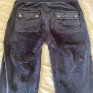  Juicy Couture byxor - Mörkblå mjukisbyxor från Juicy Couture i velour med snörning i midjan, stora fickor bak med guldknappar och broderad JC-logga framtill. Lite noppriga i midjan på insidan men syns ju inte!!💗