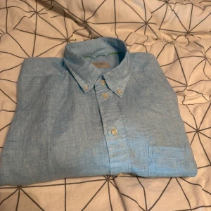 Ljusblå linneskjorta från Eton - Snygg ljusblå slim fit skjorta från Eton i svalt linne. Klassisk krage med knappar och bröstficka. Perfekt för dig som gillar stilrena och fräscha plagg med en avslappnad vibe. Enbart testad, aldrig använd. Storlek är L, 41. 