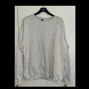 Grå sweatshirt från H&M, storlek XL - Enkel och stilren grå sweatshirt från H&M i storlek XL. Tröjan har rund halsringning, långa ärmar och ribbade muddar vid ärmslut och nederkant. 