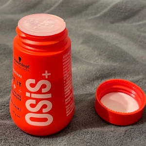 Schwarzkopf Volympuder - Osis+ Dust It är ett mattande volympuder för håret som ger extra textur och stadga. Kommer i en röd plastburk på 10g. Perfekt för att skapa volym och en matt finish utan att tynga ner håret. Vegansk formula och enkel att applicera i torrt hår.