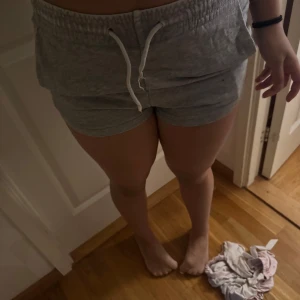 Grå mjuka shorts från H&M XS - Superbekväma grå shorts från H&M i storlek XS. De har elastisk midja med vit snörning och är tillverkade i mjuk bomullsmix. Perfekta för chill dagar eller träning. Klassisk modell med loose fit och enkel design.