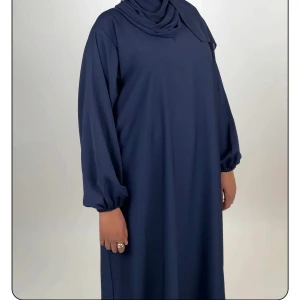 Marinblå abaya med stängda ärmar - Snygg marinblå abaya med lös passform och stängda ärmar. Klänningen har en enkel och stilren design utan mönster, perfekt för dig som gillar minimalistiskt mode. Tillverkad i ett mjukt och lätt material som faller fint. Från luude collection