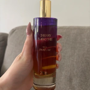 ZARA Cherry Smoothie Eau de Parfum - Cherry Smoothie från ZARA är en Eau de Parfum med fruktiga toner av körsbär och plommon, balanserat med mandel, svart vanilj och tonkaböna. Flaskan är cylinderformad i lila och bärnstensfärgat glas med guldfärgad kork. Volym: 80 ml. Knappast använt 
