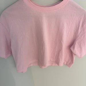 Ljusrosa croppad topp - Superfin ljusrosa croppad topp från FSBN Sister i mjuk bomull. Enkel design med rund halsringning och korta ärmar, perfekt till jeans eller kjol. Snygg och basic för en chill look.