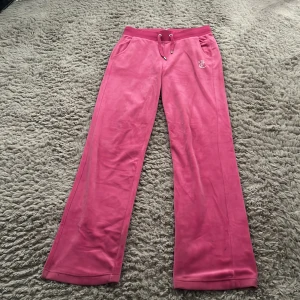 Juicy Couture rosa mjukisbyxor - Säljer ett par ikoniska rosa mjukisbyxor från Juicy Couture i mjuk velour. Byxorna är knappt använda men eftersom de är för långa har de släpats lite i marken annars helt i ny skick💓