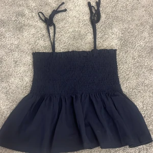 Mörkblå linnetopp ifrån SHEIN  - Supersöt mörkblå linnetopp med smockad överdel och volang nertill. Axelbanden knyts på axlarna för en personlig touch. Perfekt till jeans eller kjol när du vill ha en chill men ändå snygg look.