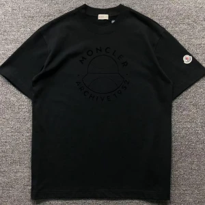 Svart Moncler t-shirt med tryck - Svart t-shirt från Moncler med diskret svart tryck på bröstet där det står 'Moncler Archive 1952'. Klassisk passform, rund hals och korta ärmar. Liten Moncler-logga på vänster ärm. Perfekt för en clean och stilren look.