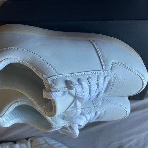 Vita DiscoSneakers från PartyFunLights - Snygga helvita sneakers från PartyFunLights, modell DiscoSneakers. Skorna har klassisk design med rund tå, snörning och platt sula i gummi. Ovandelen är i syntetmaterial och insidan är vadderad för extra komfort. Perfekta för dig som gillar stilrena och fräscha sneakers.