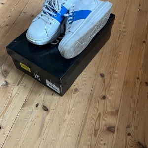 Giras skor - Säljer mina vita grusa skor, använda ett fåtal gånger. Stilrena skor med blå rand på ut och insida av skon. Storlek 40. Skoldåd ingår 