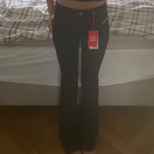 Mörkblå bootcut jeans från Diesel - Snygga mörkblå jeans från Diesel med bootcut passform och kontrastsömmar. Klassisk femficksmodell med låg midja och tydlig Diesel-logga bak. Jeansen är i jeansmaterial och har en stilren look som passar till det mesta.