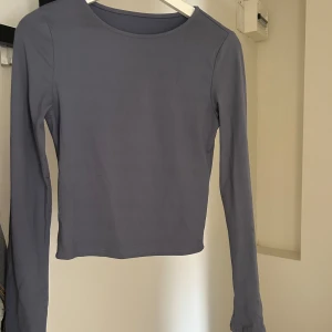 Ljusblå/grå långärmad croppad topp - En stilren långärmad topp med croppad passform. Enkel och clean design med rund halsringning. 