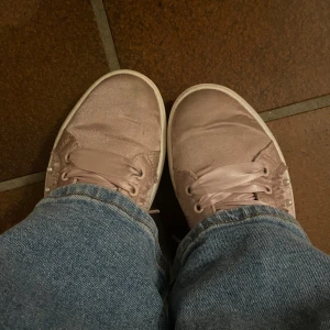 Rosa sneakers med pärldetaljer - Så fina, rosa sneakers i satin med pärldetaljer på sidan!! Skorna har matchande rosa snören och en vit sula💕 Perfekta att ha i skolan, passar även bra att ha när man ska klä upp sig. Pris kan diskuteras 🥰 