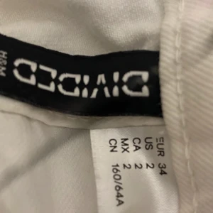 Vita shorts från H&M Divided - Snygga vita shorts från H&M Divided med fransiga kanter. Perfekta för sommardagar. De har en klassisk femficksdesign och knappstängning fram.