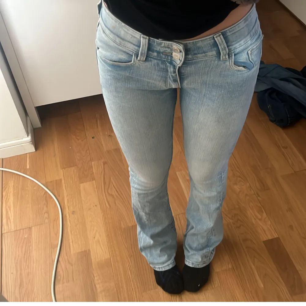 Snygga ljusblå jeans med bootcut-stil och låg midja. . Farkut & Housut.