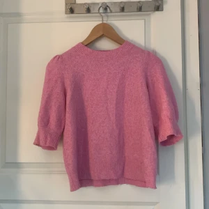 Rosa stickad tröja från Vero Moda - Säljer en söt rosa stickad tröja från Vero Moda. Tröjan har puffiga trekvartsärmar och en rund halsringning. Perfekt för en mysig dag.