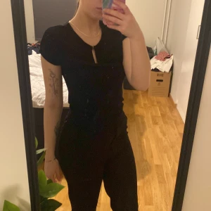 Svart kortärmad blus från vero moda - Säljer en stilren svart topp/blus från Vero Moda med korta ärmar och en liten knappdetalj vid halsen. Perfekt för en enkel och elegant look. Passar bra till både jeans och kjol eller kostymbyxor. 