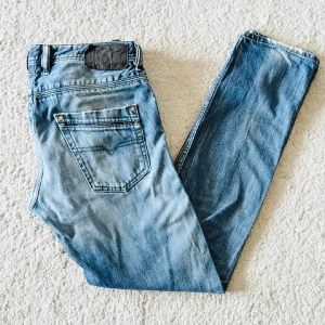 Blå Diesel jeans - Säljer dessa snygga jeans från diesel! Dom har en otroligt skön ljusblå wash med en snygg design på bakfickan och har en slim passform. Midja 30, Längd 32. Hör av er!