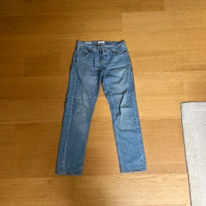 Blå jeans från Jack & Jones - Säljer ett par klassiska blå jeans från Jack & Jones. De har en loose fit och är perfekta för en avslappnad stil. Jeansen har en dragkedja och knappar framtill.