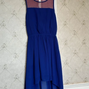 Blå klänning perfekt för sommaren - Säljer en elegant blå klänning med en prickig mesh-detalj upptill. Klänningen har en luftig passform och en asymmetrisk nederdel som ger en fin rörelse. Perfekt för speciella tillfällen! STORLEK=146cl