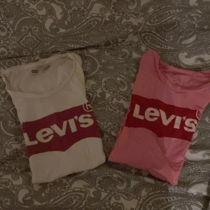 T-shirt från Levi's i vitt och rosa - Två snygga t-shirts från Levi's, en i vitt och en i rosa, med det klassiska Levi's-logotypen tryckt i rött på bröstet. Perfekta för en casual look!