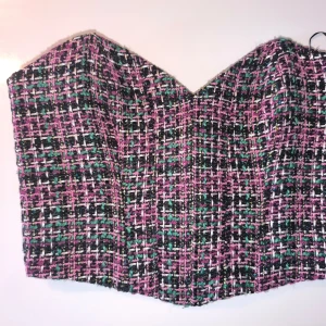 Flerfärgad korset topp från Zara - Säljer en snygg korset topp från Zara i ett flerfärgat rutigt mönster med inslag av rosa, grön, svart och vit. Toppen har en stilren design och är perfekt för att lyfta vilken outfit som helst. Passar bra till både jeans och kjol.