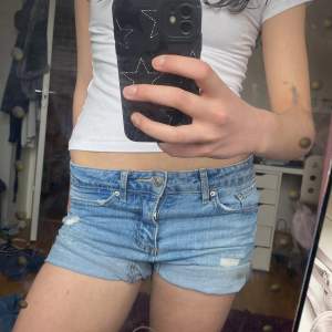 Säljer ett par blå jeansshorts med slitna detaljer och upprullade benslut. Perfekta lågmidjade för sommardagar och en avslappnad stil. De har en klassisk femficksdesign och knappgylf. Storlek är 150 men passar bra för 150-160 också! Jag är 160 och känner att de börjar bli lite små på mig💕